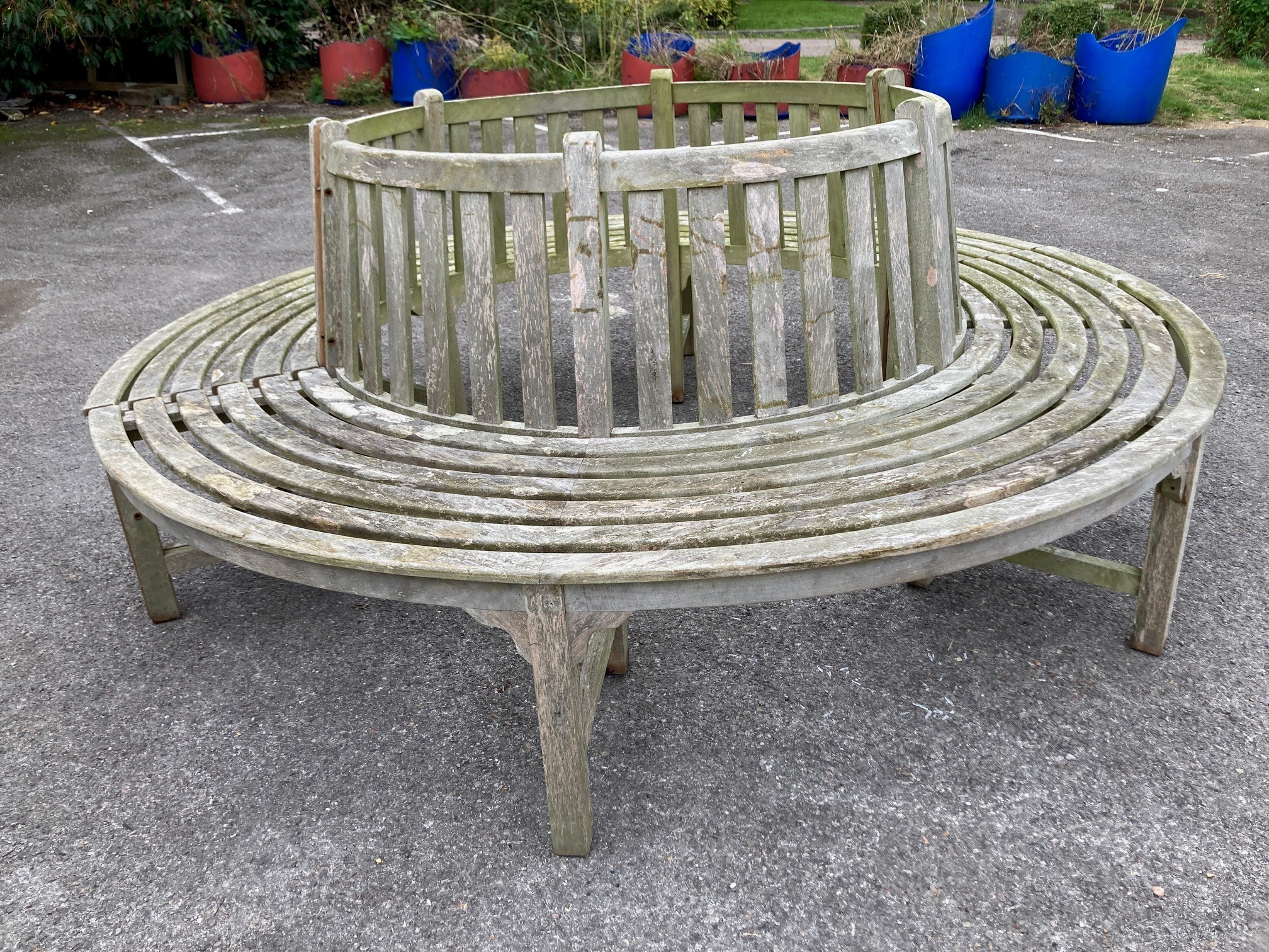 A weathered teak two section garden tree seat, diameter approx. 210cm, height 87cm, aperture approx. 116cm